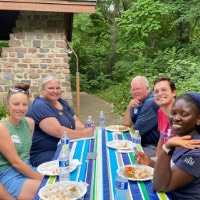 6 GVSU Alumni sit together and smile on a John Ball Zoo picnic table